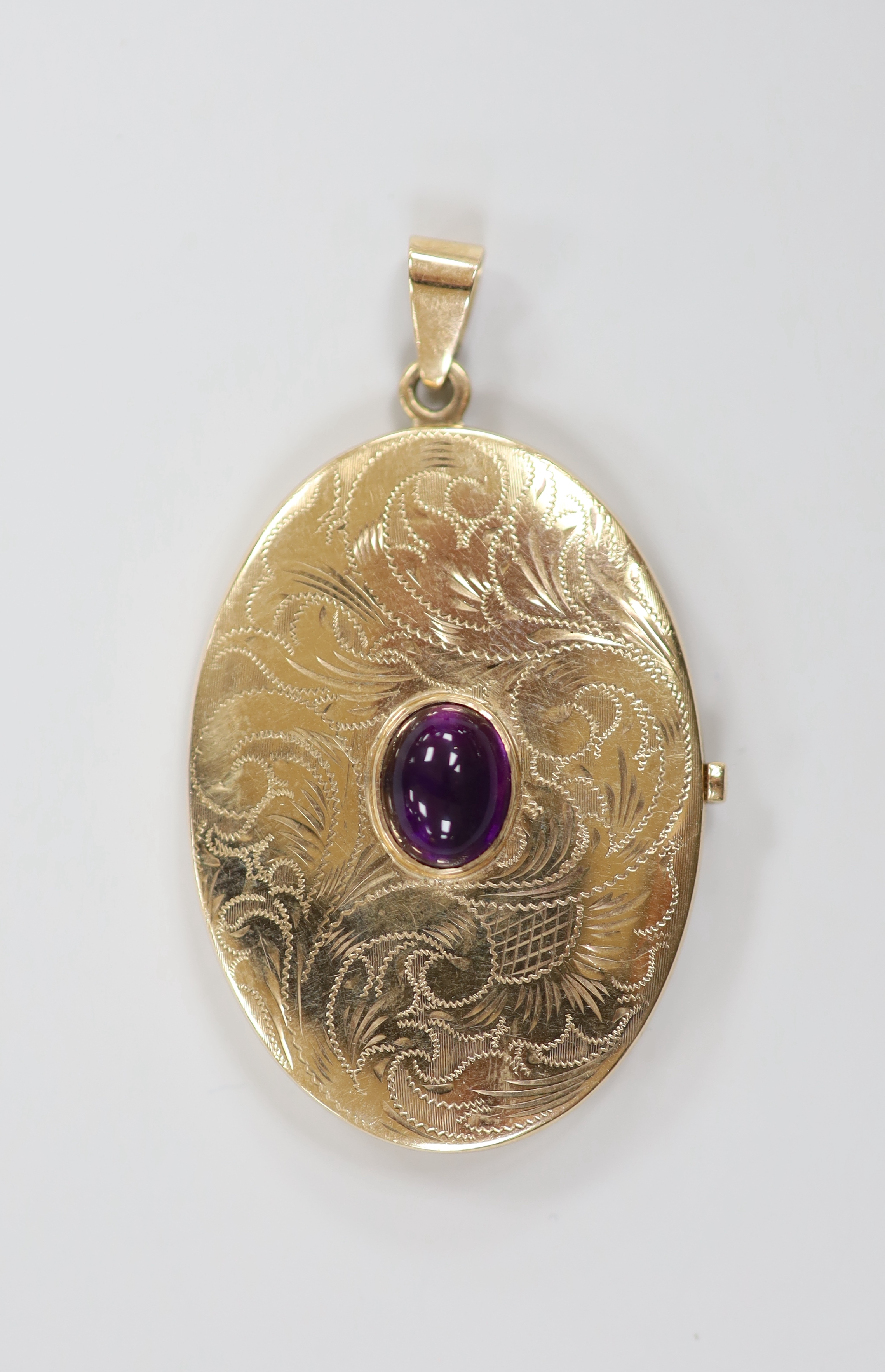 A modern engraved 9ct gold and cabochon garnet set oval pendant locket, overall 56mm, gross weight 14.2 grams.